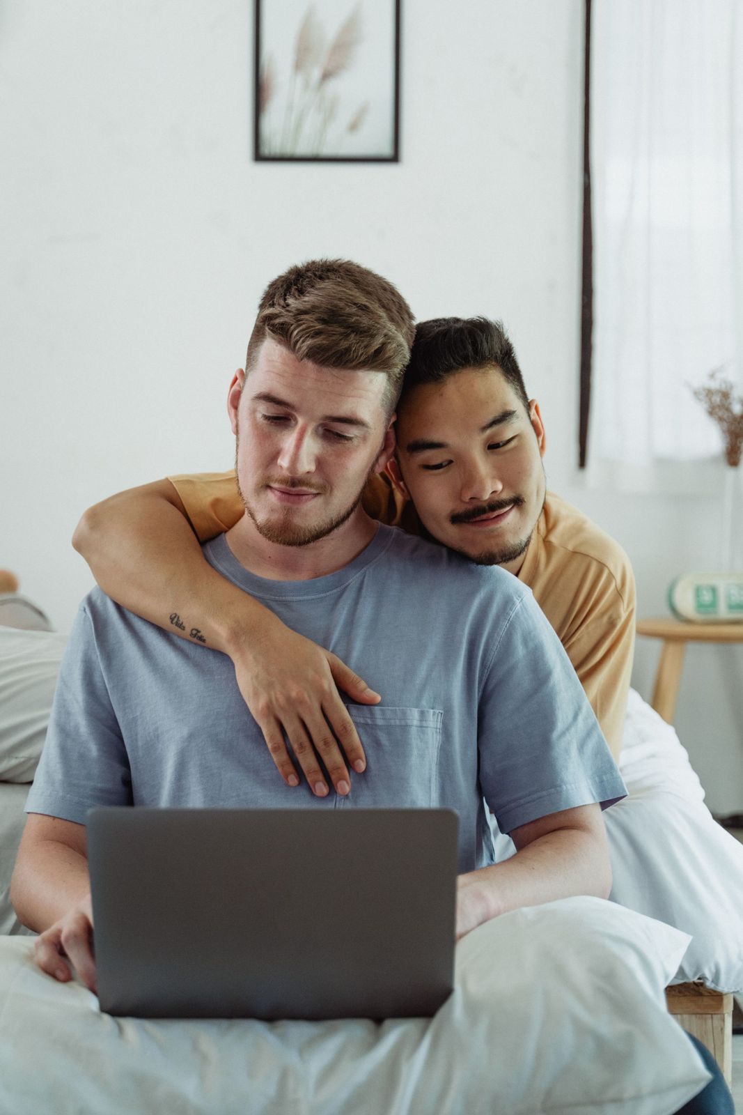 Two men sharing a laugh while looking at a laptop at home