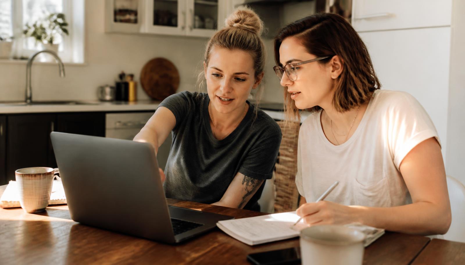 Same-sex couple reviewing family-building finances and paperwork at a kitchen table